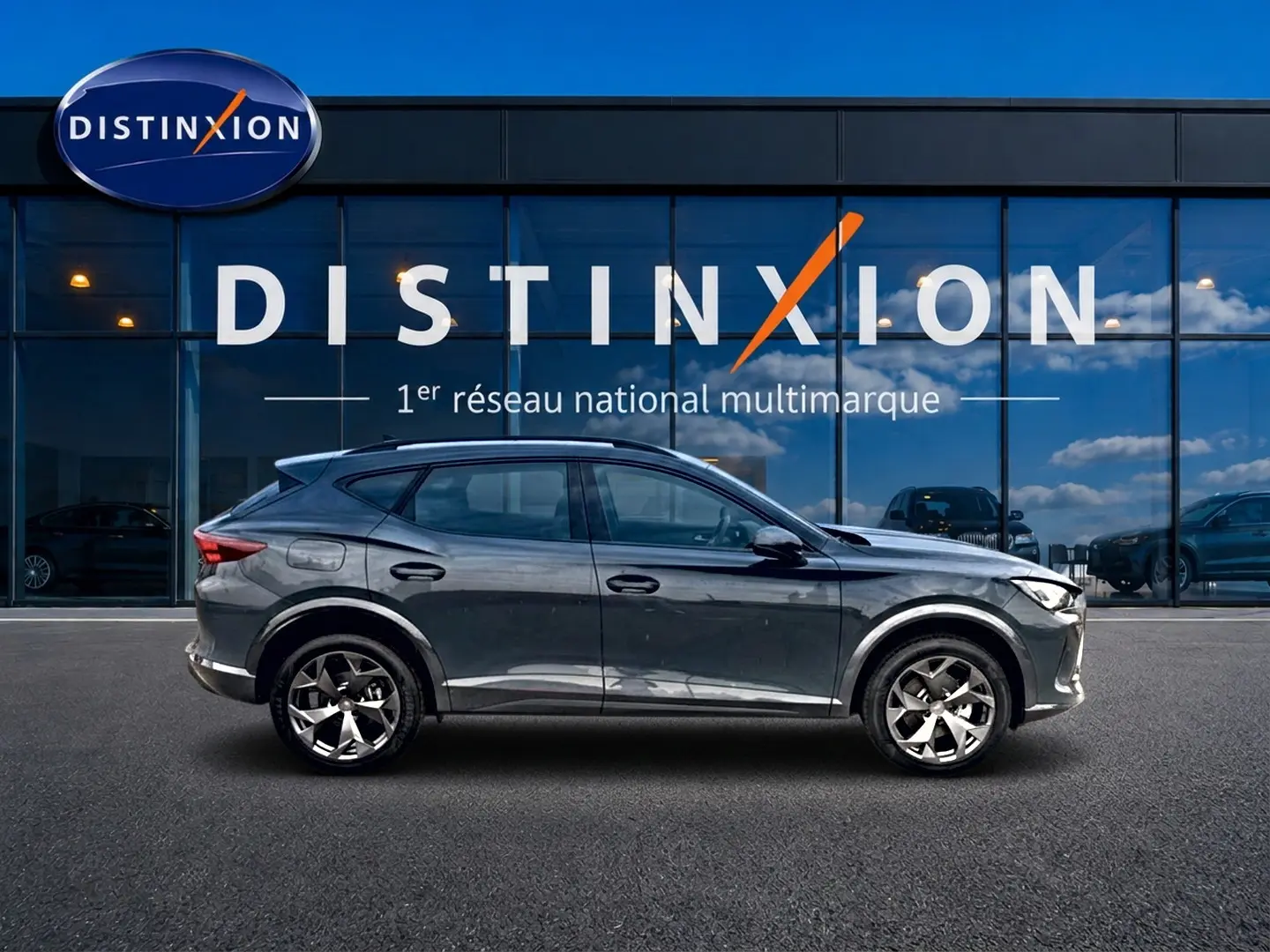 Vue latérale droite d'un CUPRA Formentor bleu fjord 2026 garé devant une vitrine avec logo Distinxion.