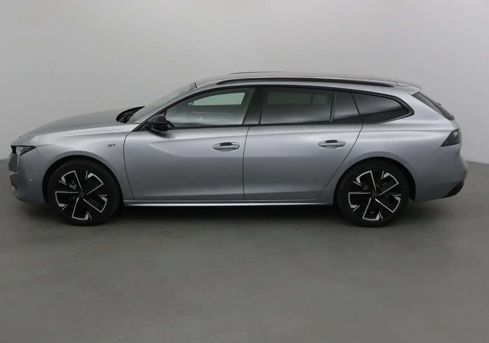 Peugeot 508 SW gris Artense vue profil côté gauche, avec jantes noires et badge GT visible sur l'aile avant.