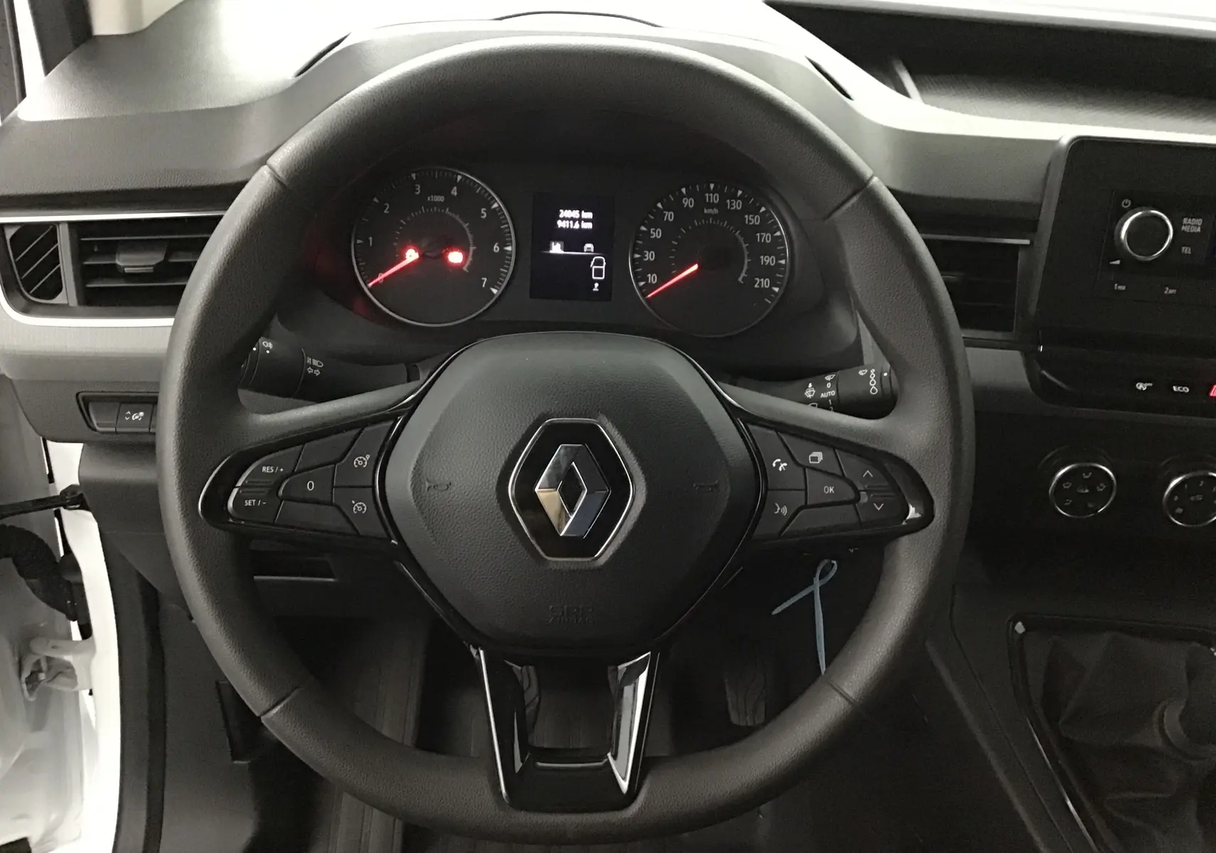 Vue rapprochée du volant noir du Renault Kangoo blanc 2022, avec commandes intégrées et tableau de bord visible.