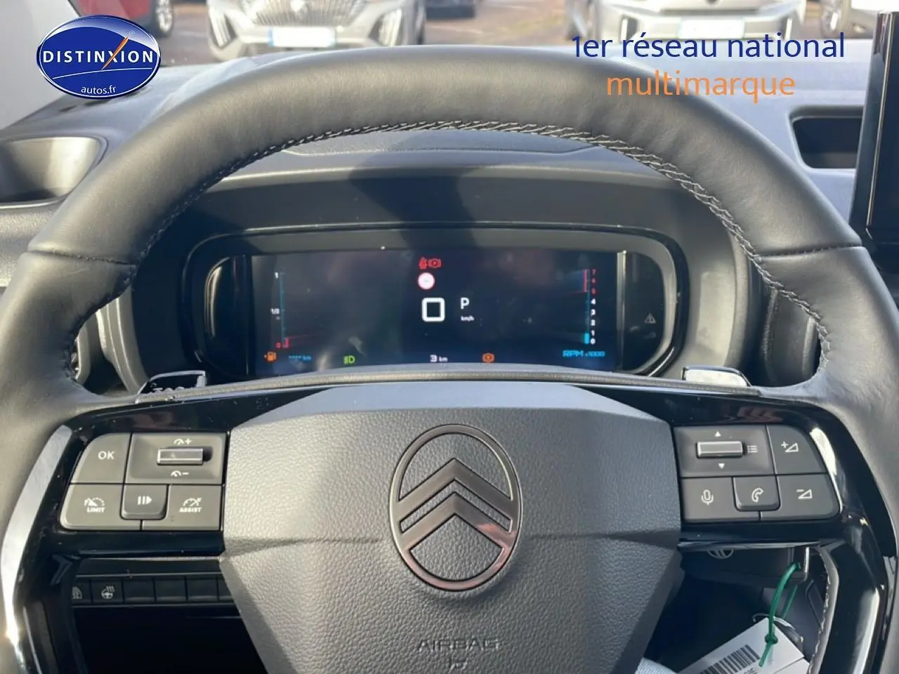 Vue rapprochée du volant cuir multifonction de la Citroën Berlingo gris Artense avec tableau de bord numérique allumé.