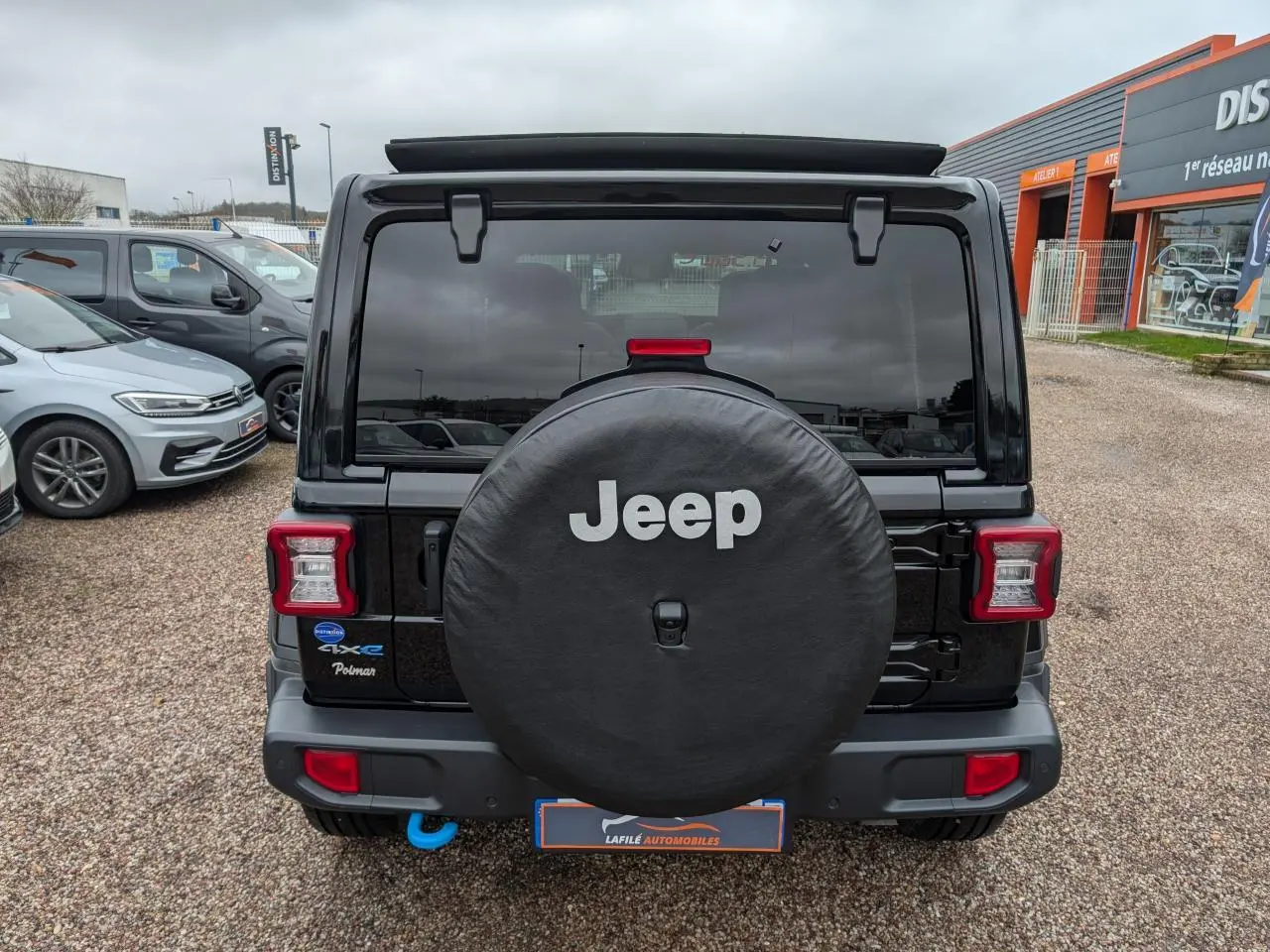 Vue arrière d'un Jeep Wrangler noir avec roue de secours couverte et feux arrière LED carrés.