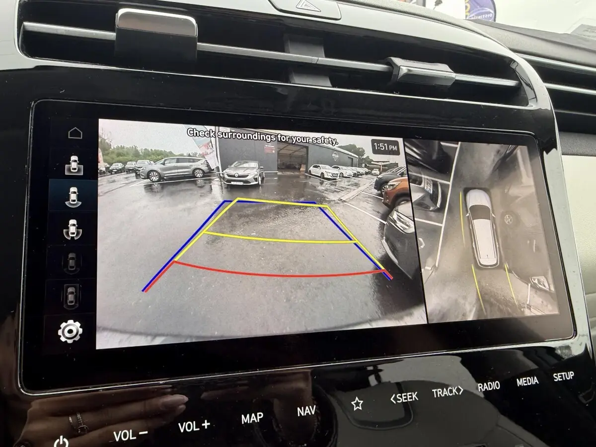 Écran tactile intérieur du Hyundai Tucson 1.6 Hybrid gris foncé montrant la caméra de recul et la vue à 360° en stationnement.