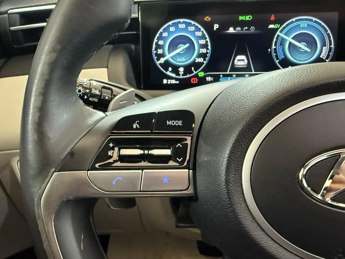 Gros plan sur le volant cuir et alu du Hyundai Tucson 1.6 Hybrid 230 Executive, avec tableau de bord digital affichant la vitesse.