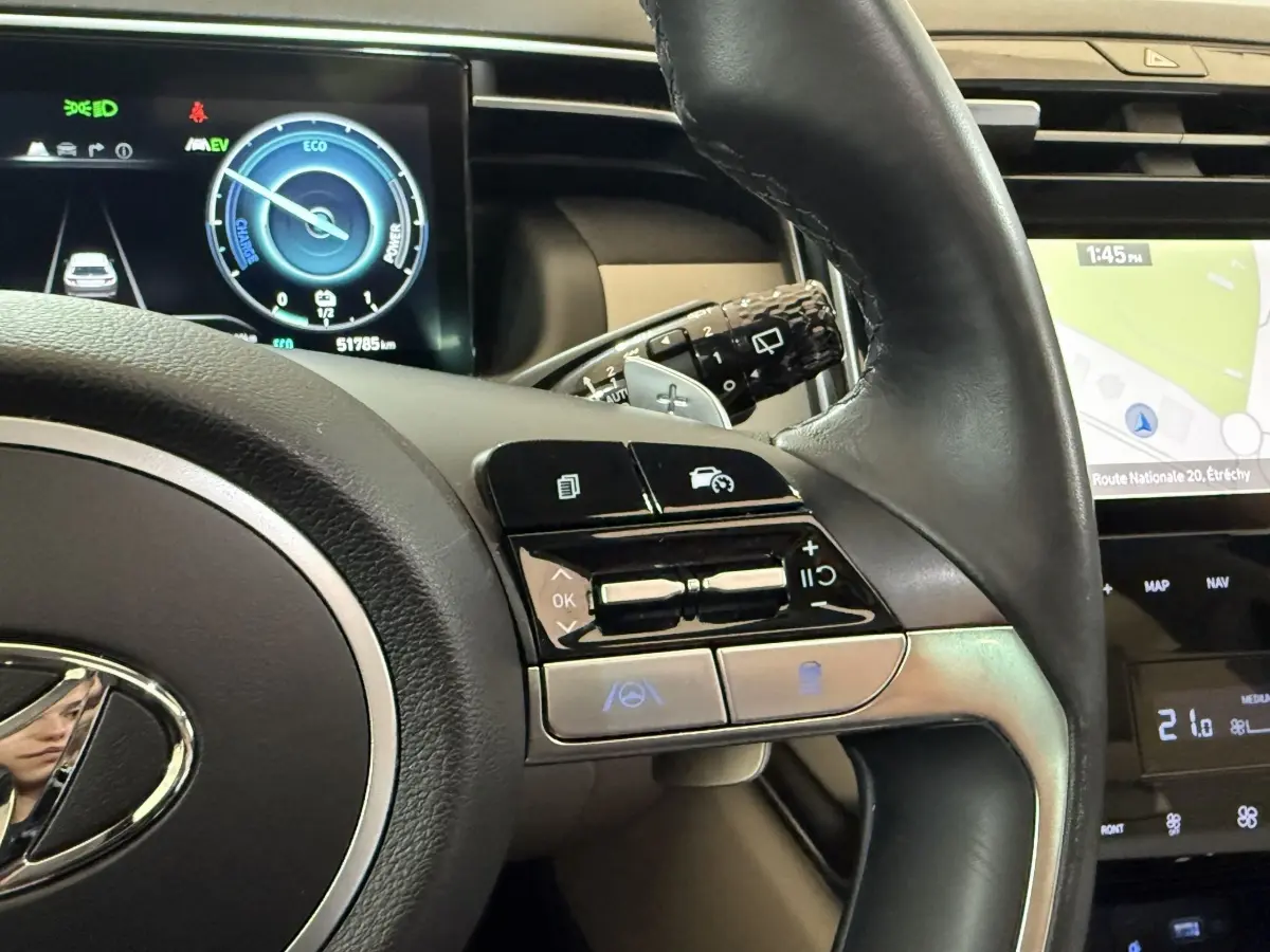 Vue rapprochée du volant droit en cuir du Hyundai Tucson gris foncé avec commandes multifonctions et écran tactile de navigation.