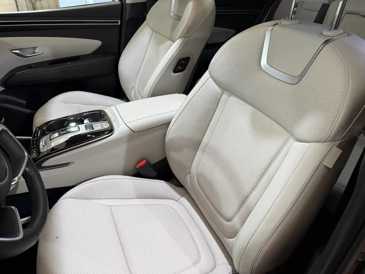 Vue intérieure côté conducteur du Hyundai Tucson 1.6 Hybrid 230 Executive avec sièges en cuir beige clair et console centrale moderne.