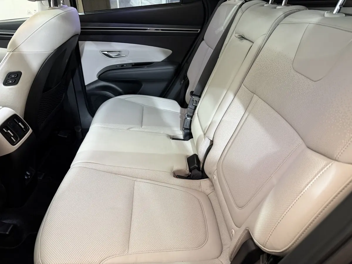 Vue latérale des sièges arrière en cuir beige clair du Hyundai Tucson 1.6 Hybrid 230 Executive, intérieur spacieux et soigné.