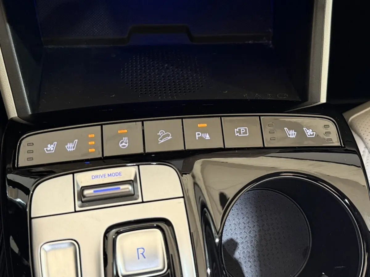 Gros plan sur la console centrale du Hyundai Tucson gris foncé, avec boutons de sièges chauffants et mode de conduite.