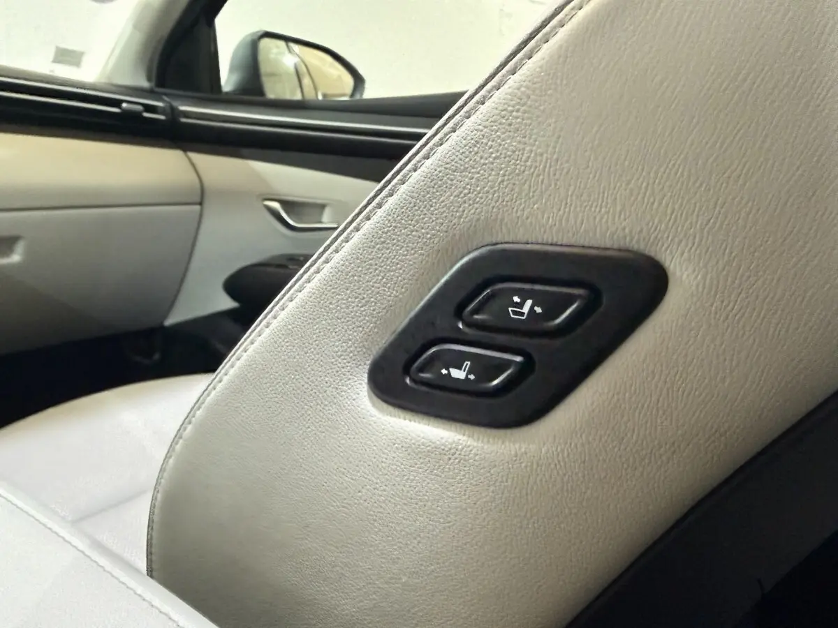 Détail des commandes de réglage des sièges arrière en cuir clair dans un Hyundai Tucson gris foncé.