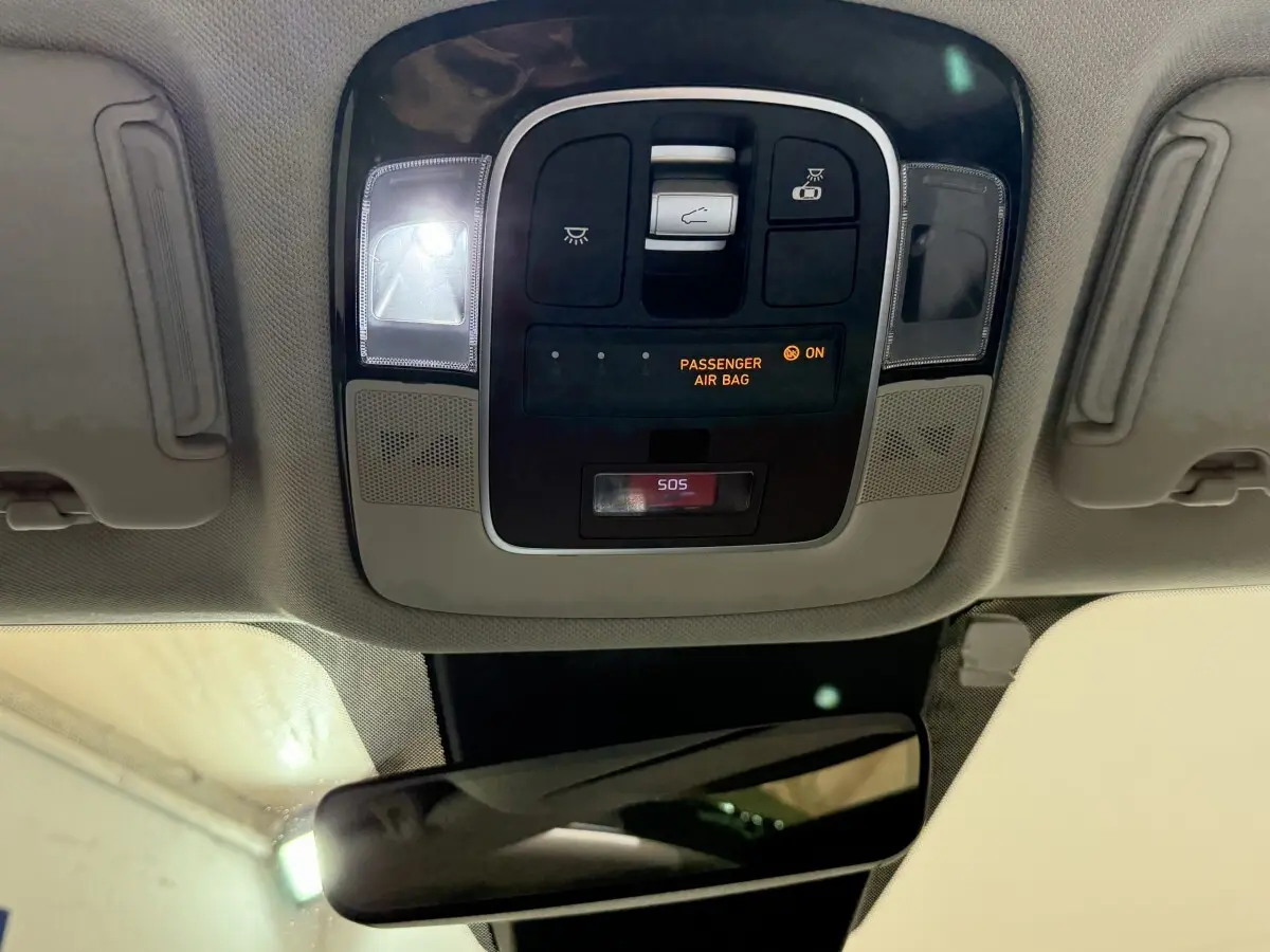 Vue intérieure du plafonnier du Hyundai Tucson gris foncé 2021 avec commandes d’éclairage et indicateur airbag passager.