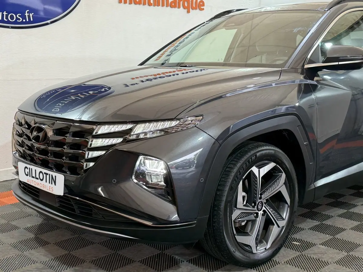 Vue 3/4 avant droit d'un Hyundai Tucson gris foncé avec calandre distinctive et jantes alliage modernes.