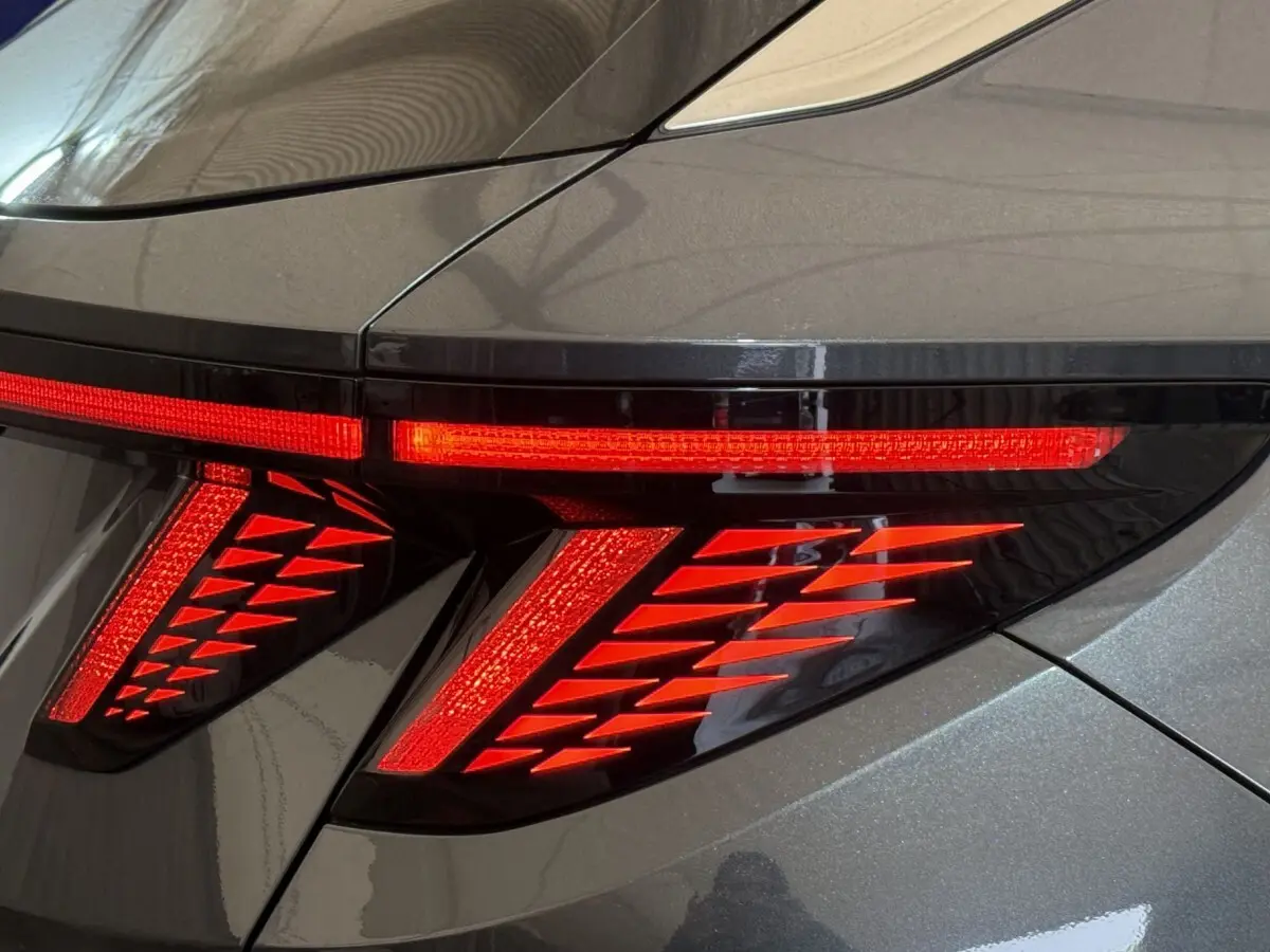 Gros plan sur le feu arrière droit rouge allumé du Hyundai Tucson 1.6 Hybrid 230 Executive gris foncé.