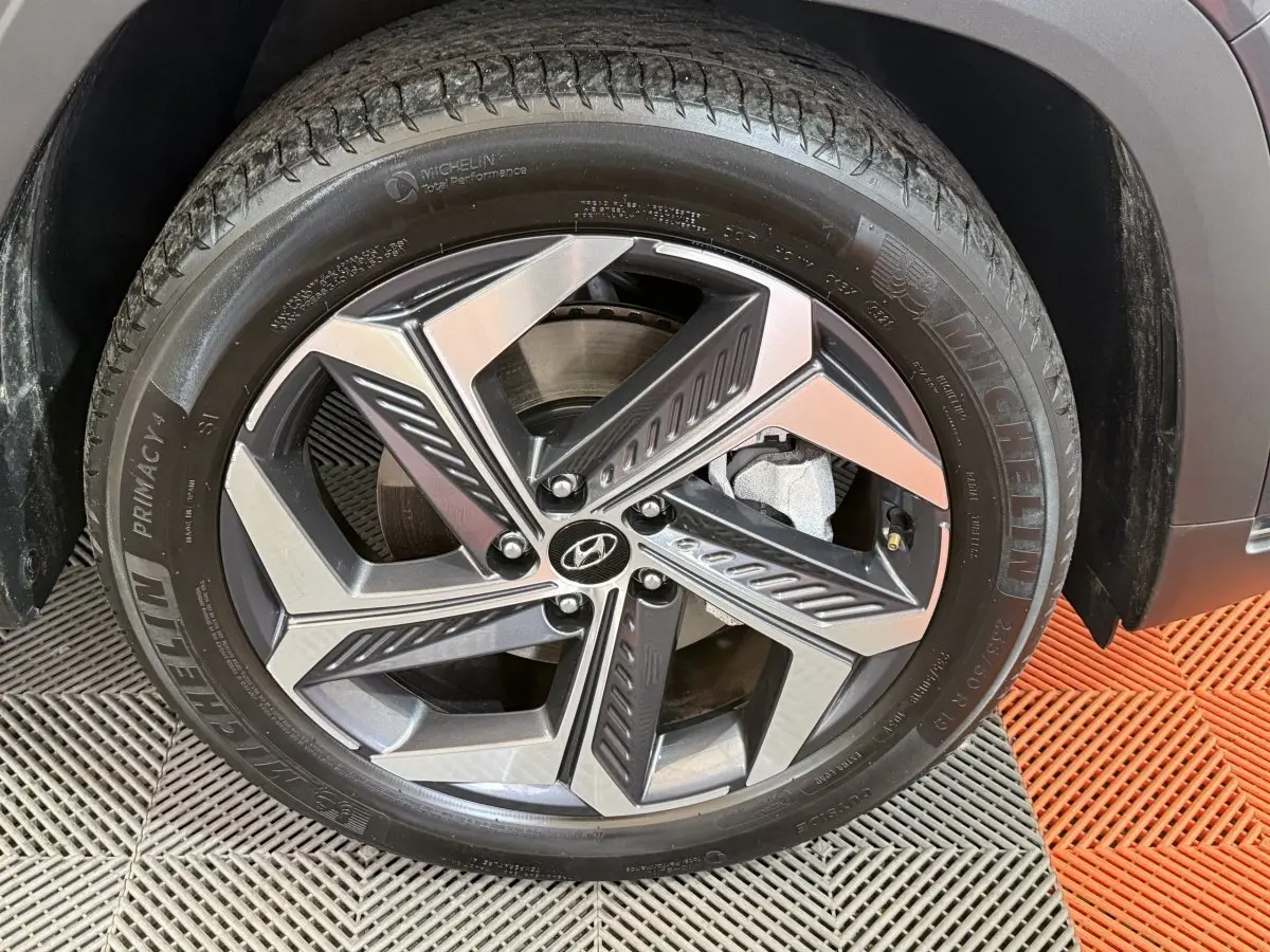 Gros plan sur la jante alliage bicolore et pneu Michelin du côté droit d’un Hyundai Tucson gris foncé.