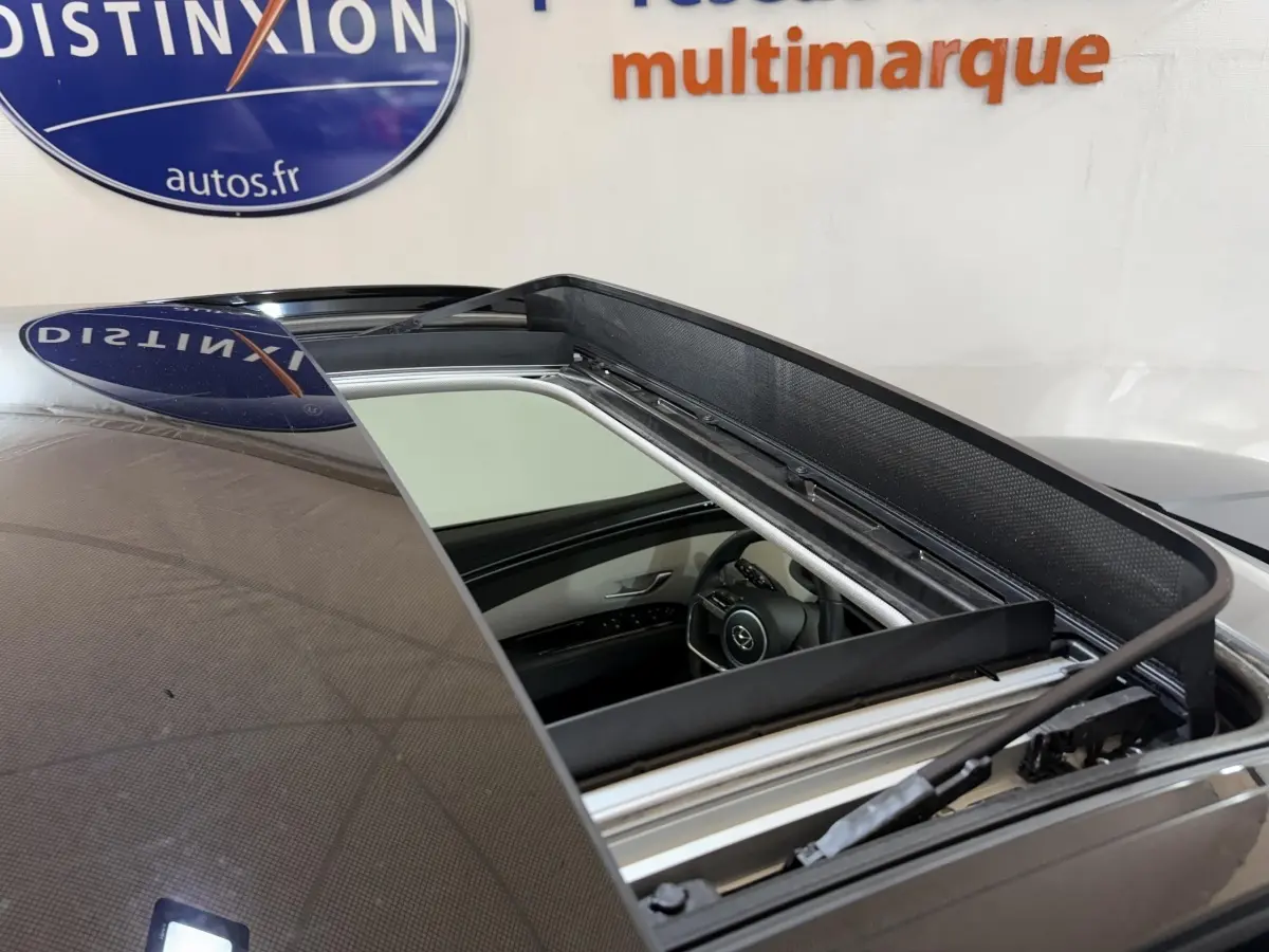 Toit ouvrant électrique ouvert sur un Hyundai Tucson gris foncé, vue rapprochée du toit et intérieur côté conducteur.