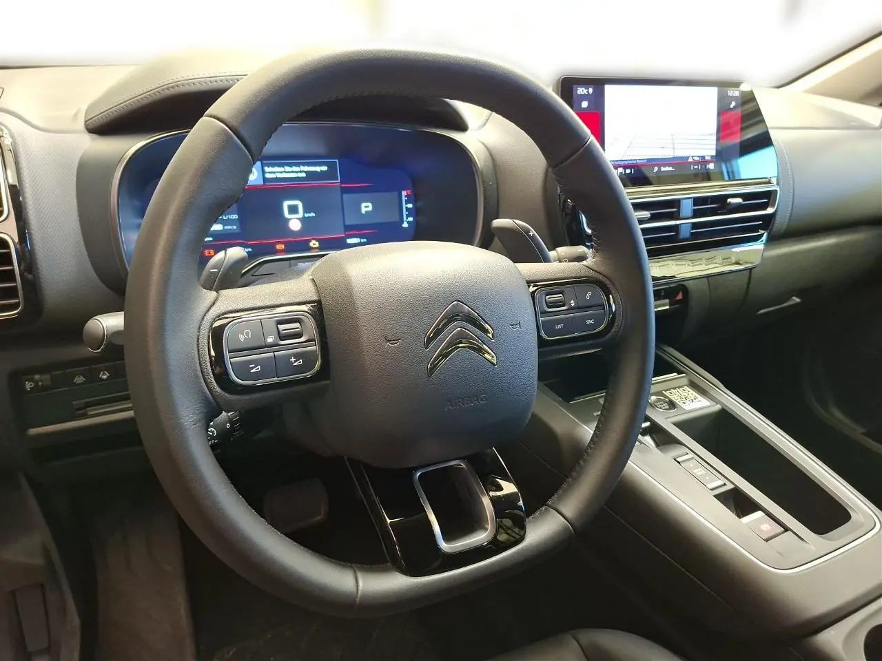Vue intérieure centrée sur le volant cuir noir et le tableau de bord numérique du Citroën C5 Aircross 2025.