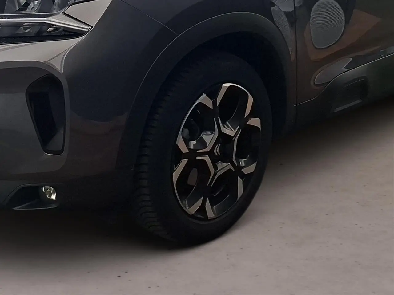 Gros plan sur la roue avant gauche et partie basse avant du Citroën C5 Aircross gris Platinium avec jante alliage 18'' bi-ton.