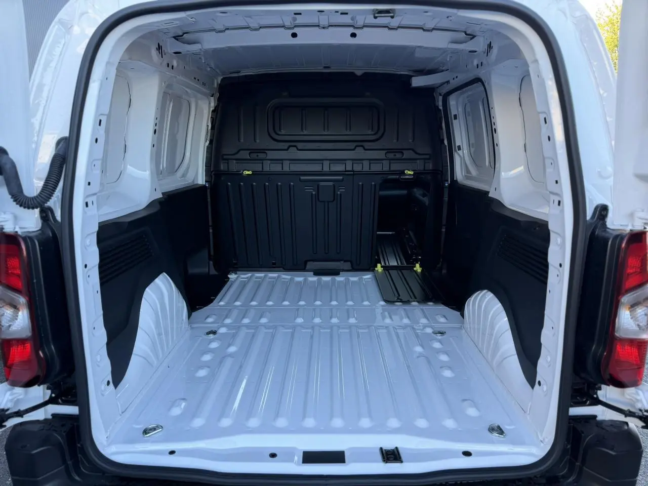 Vue arrière du coffre blanc Icy du Peugeot Partner 2026, montrant l'espace de chargement tôlé et les anneaux d'arrimage au sol.
