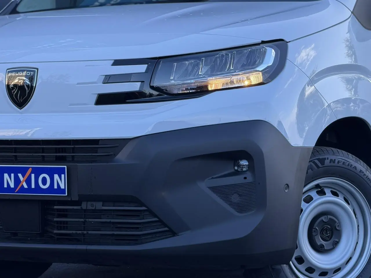 Gros plan sur l'avant droit du Peugeot Partner blanc Icy, avec phares LED et pare-chocs noir mat.
