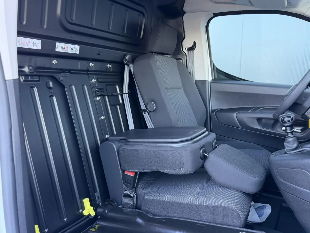 Vue intérieure côté passager du Peugeot Partner 2026 avec banquette rabattable et tablette écritoire intégrée.