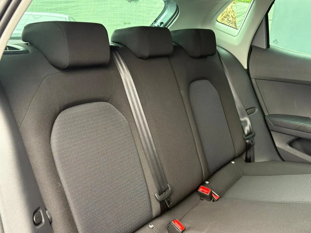 Vue intérieure du siège arrière droit de la SEAT IBIZA 2024, tissu noir avec ceinture de sécurité visible.