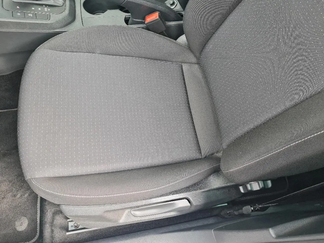 Gros plan sur le siège conducteur en tissu gris foncé de la SEAT IBIZA 2024, avec réglage manuel visible.