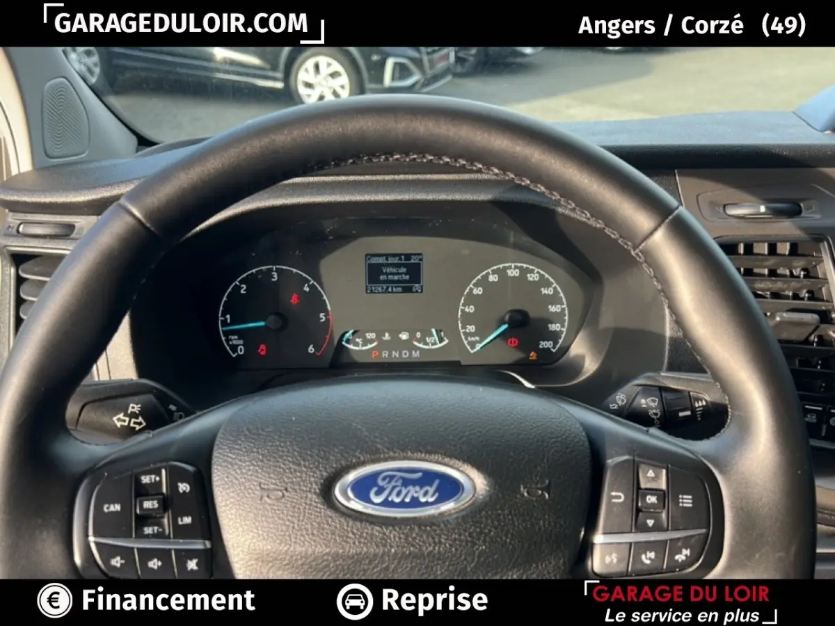 Vue intérieure centrée sur le volant en cuir noir avec logo Ford et tableau de bord du Transit Custom 2023.
