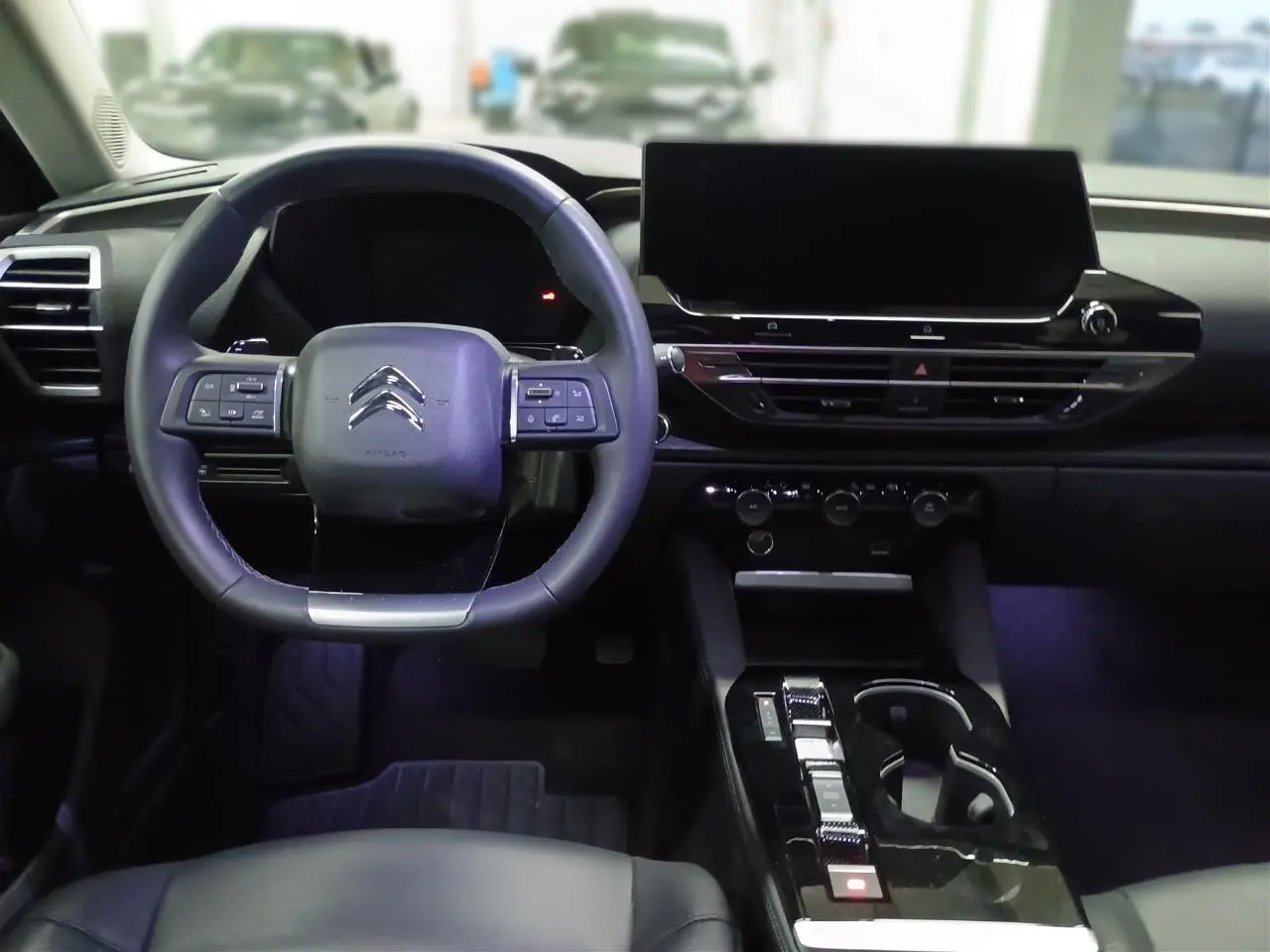 Vue intérieure avant du Citroën C5 X 2024 avec tableau de bord noir, volant cuir et écran tactile central large.
