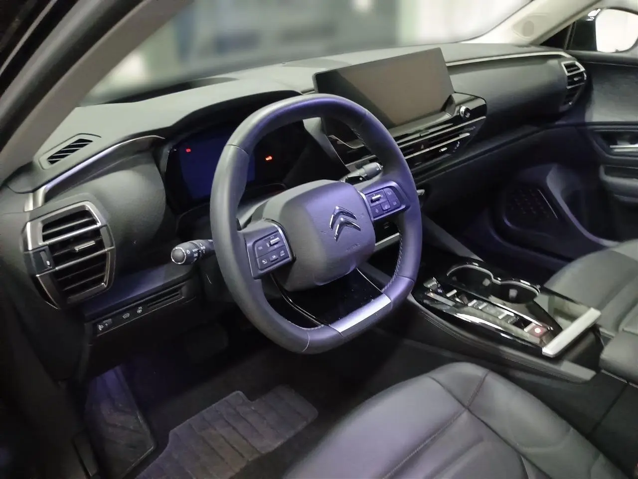Vue intérieure côté conducteur du Citroën C5 X noir Perla, avec volant cuir et écran tactile central large.