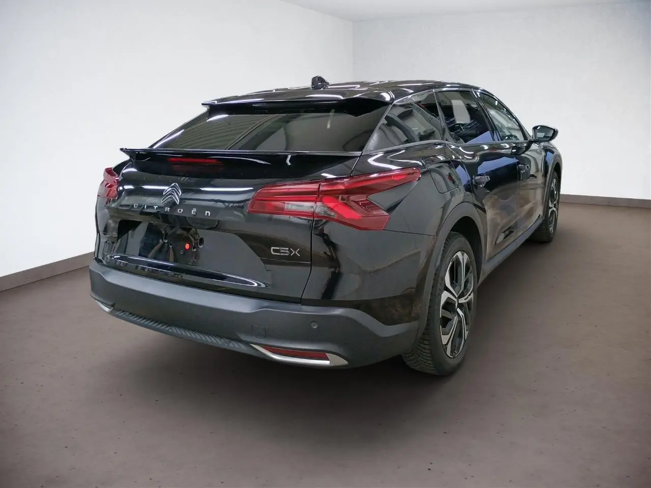 Vue 3/4 arrière droite d'une Citroën C5 X noire Perla avec feux arrière LED 3D et jantes alliage 19 pouces.