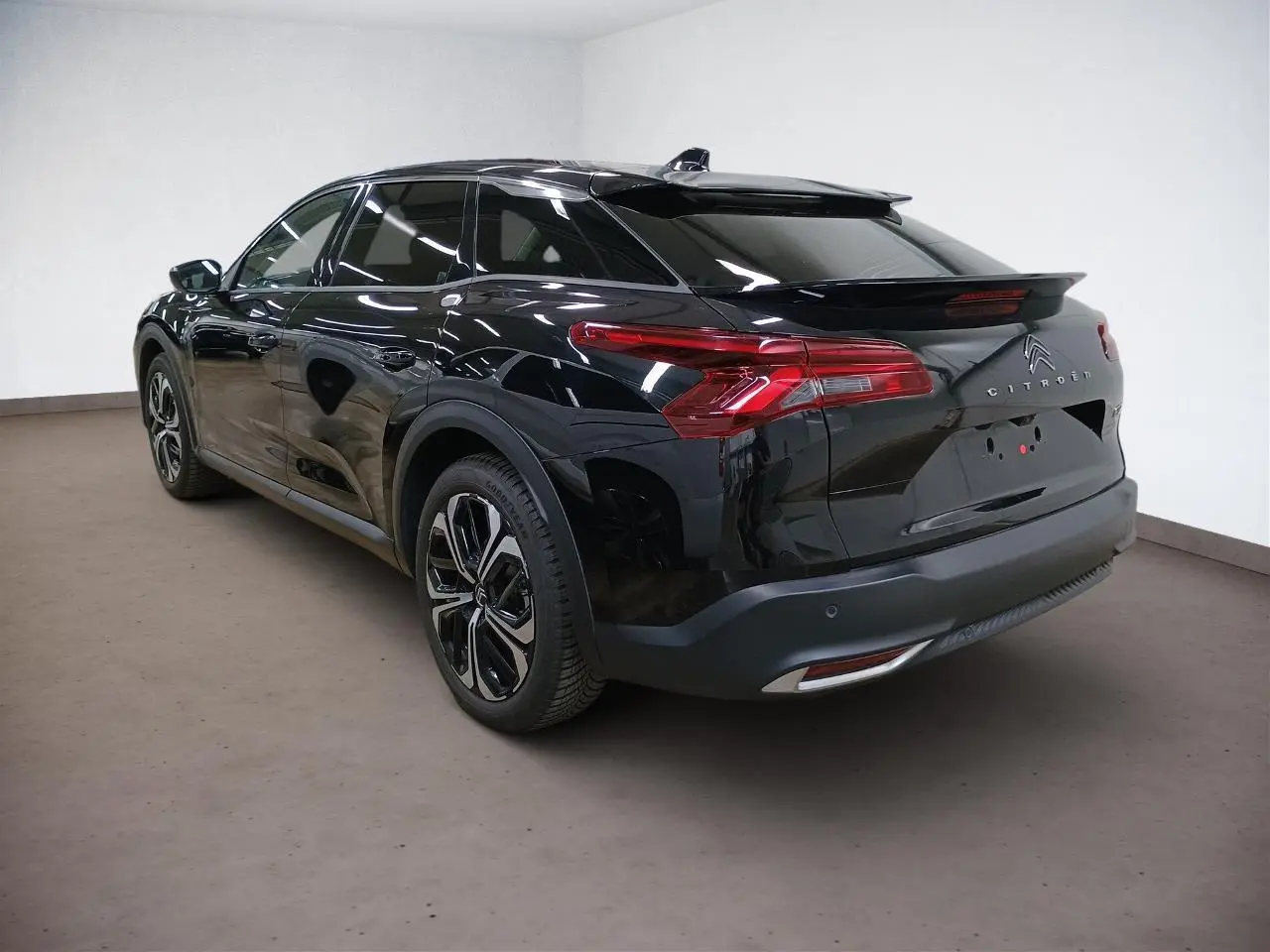 Vue 3/4 arrière droite du Citroën C5 X noir Perla, mettant en valeur ses feux arrière LED et jantes alliage 19 pouces.