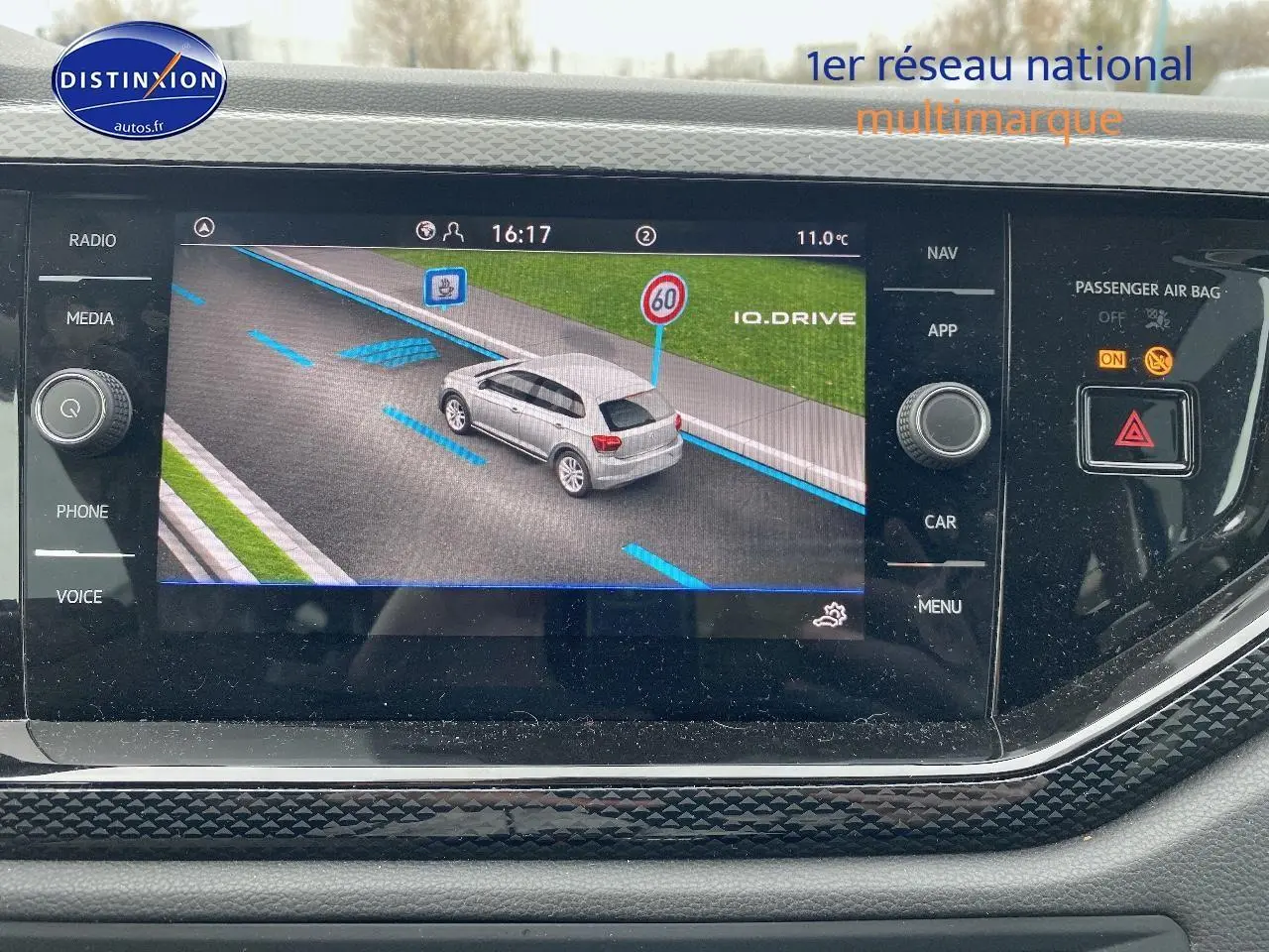 Écran de navigation affichant une Volkswagen Polo blanche vue de 3/4 arrière sur route avec limite à 60 km/h.