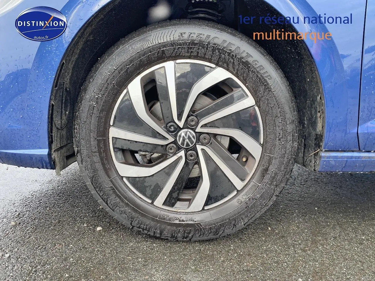 Gros plan sur la roue avant gauche avec jante alliage noire et argentée d'une Volkswagen Polo bleu récif.