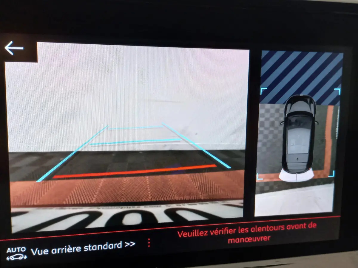 Affichage caméra de recul et vue aérienne du Peugeot 208 blanc, guidage de trajectoire visible à l'écran.
