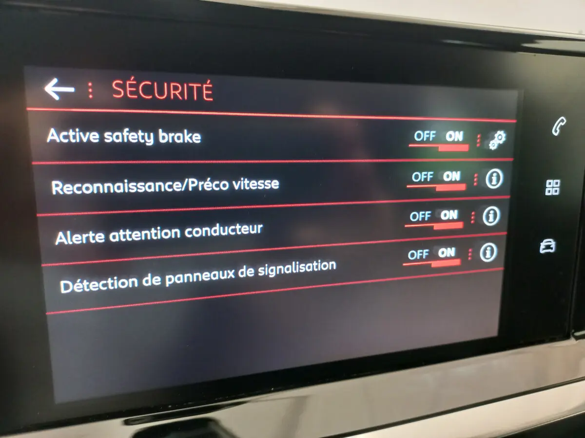 Écran tactile intérieur du Peugeot 208 blanc, affichant les options de sécurité activées.
