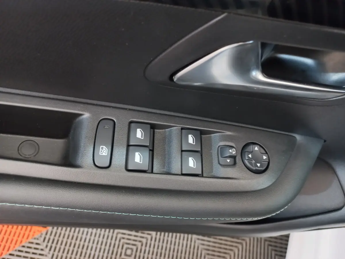 Détail des commandes des vitres et rétroviseurs sur la porte côté conducteur d’une Peugeot 208 blanche PureTech 100 S&S Allure 2021.