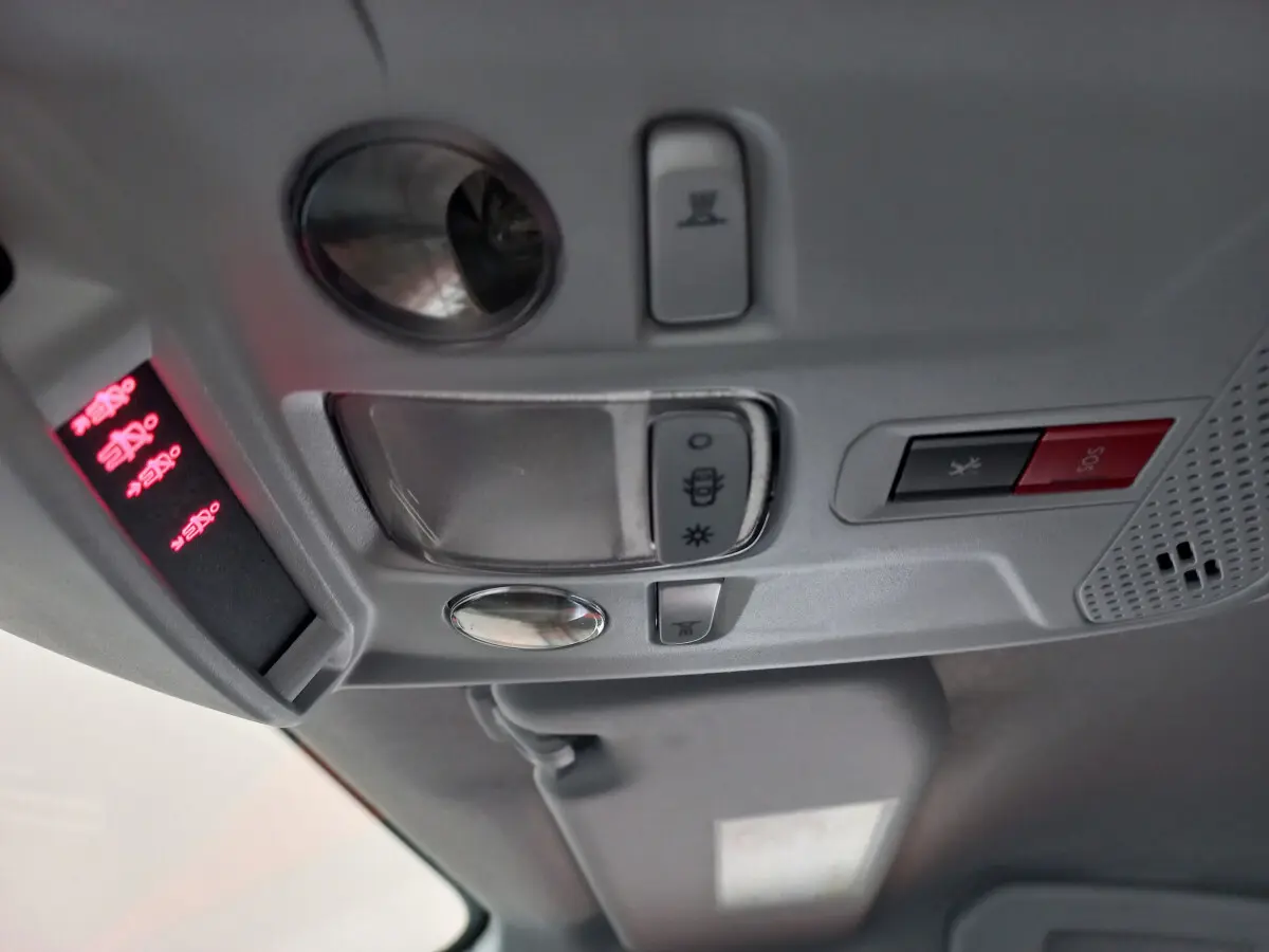 Vue en gros plan du plafonnier gris clair de la Peugeot 208 blanc avec boutons d'éclairage et alarme SOS.