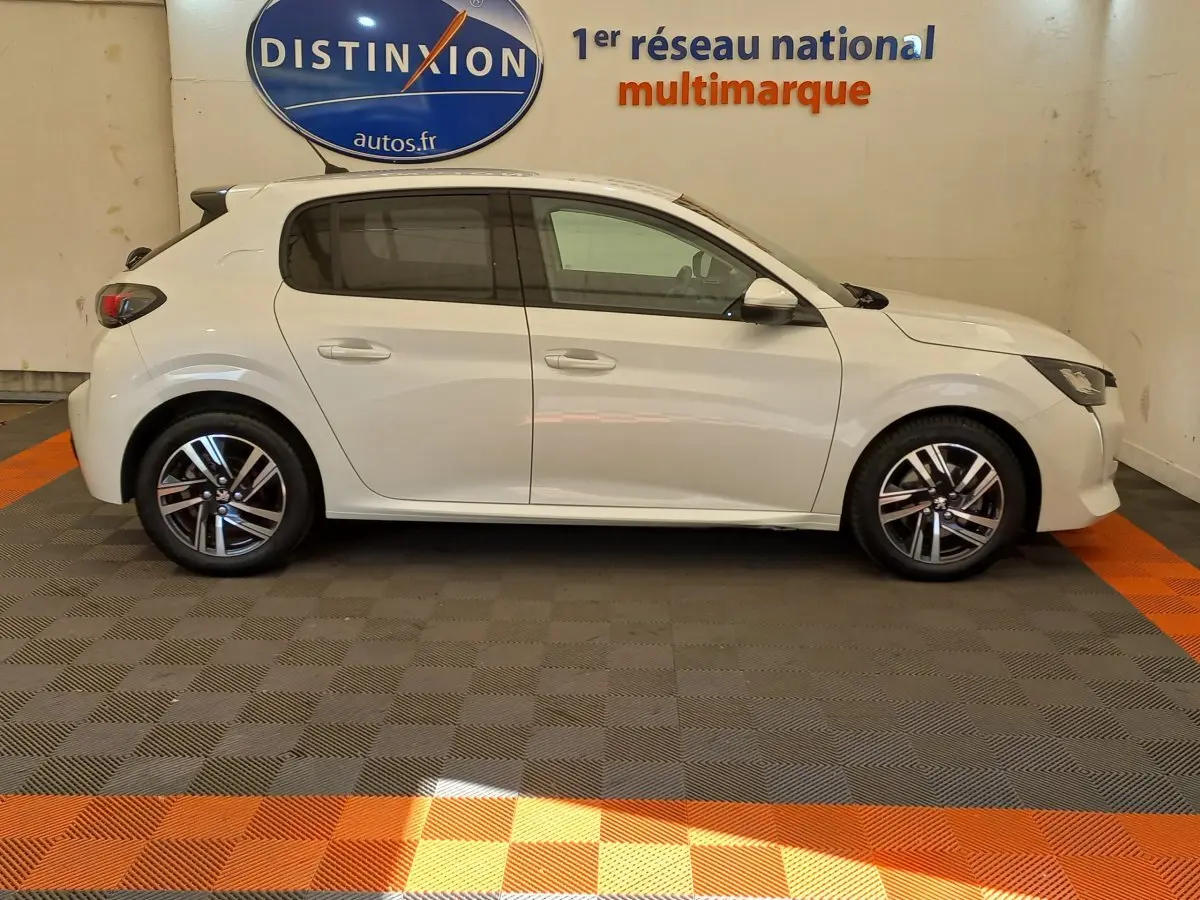 Profil droit d'une Peugeot 208 PureTech 100 S&S Allure blanche, avec jantes alliage et feux arrière LED visibles.