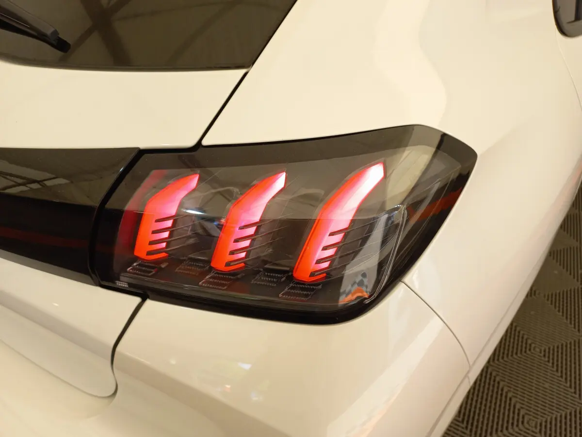 Gros plan sur le feu arrière droit rouge du Peugeot 208 blanc, soulignant son design moderne et distinctif.