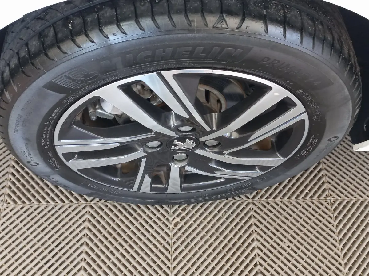 Gros plan sur la roue avant droite d'une Peugeot 208 blanche avec jante alliage et pneu Michelin.