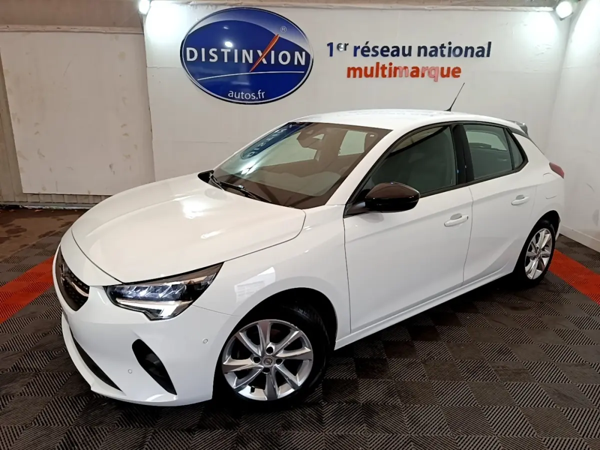 Vue 3/4 avant d'une Opel Corsa blanche 2023 avec jantes alliage et rétroviseurs noirs en intérieur showroom.