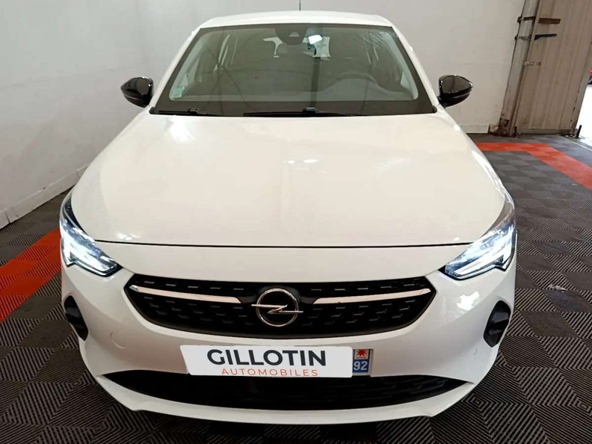 Vue avant d'une Opel Corsa blanche 2023 avec phares LED allumés et calandre noire distinctive.