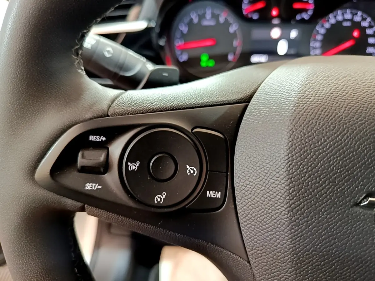 Gros plan sur le volant cuir noir de l’Opel Corsa 2023, avec commandes de régulateur de vitesse visibles.