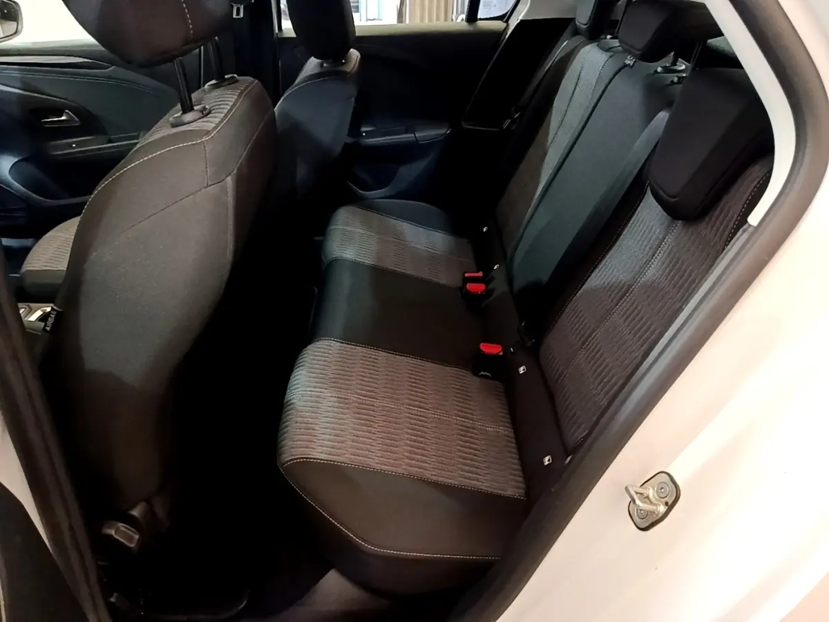 Vue intérieure depuis la porte arrière droite sur la banquette arrière tissu gris et noir de l’Opel Corsa blanc.