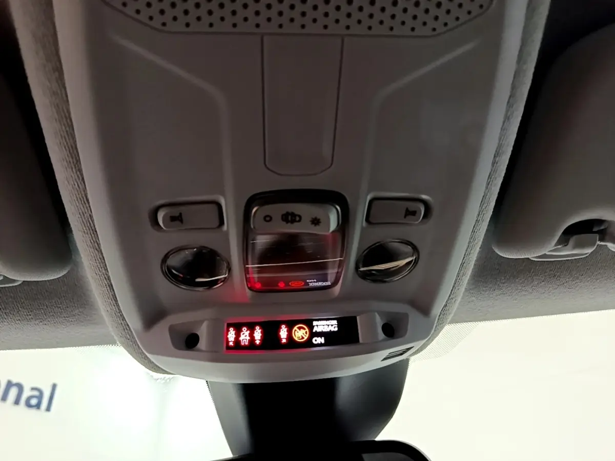 Vue intérieure du plafonnier avant de l’Opel Corsa blanc, avec commandes d’éclairage et affichage airbag actif.