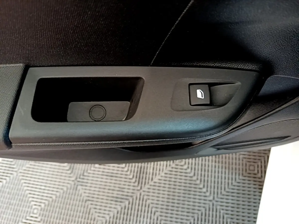 Gros plan sur la commande de lève-vitre électrique côté porte intérieure d'une Opel Corsa blanche de 2023.