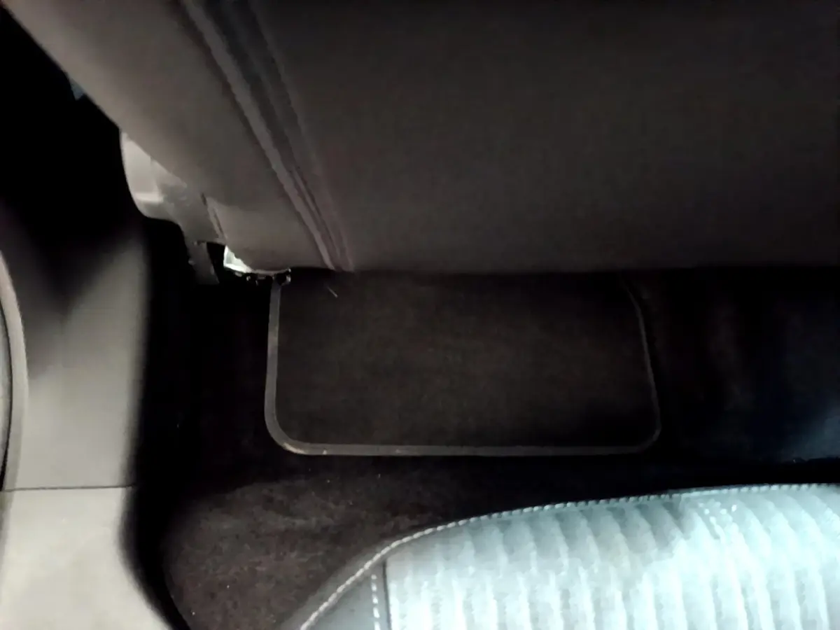 Détail de la moquette et tapis de sol noir sous la banquette arrière d’une Opel Corsa blanche 2023.