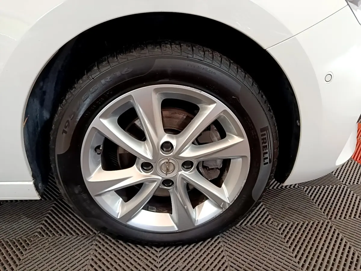 Gros plan sur la roue avant droite d’une Opel Corsa blanche avec jante alliage et pneu Pirelli.