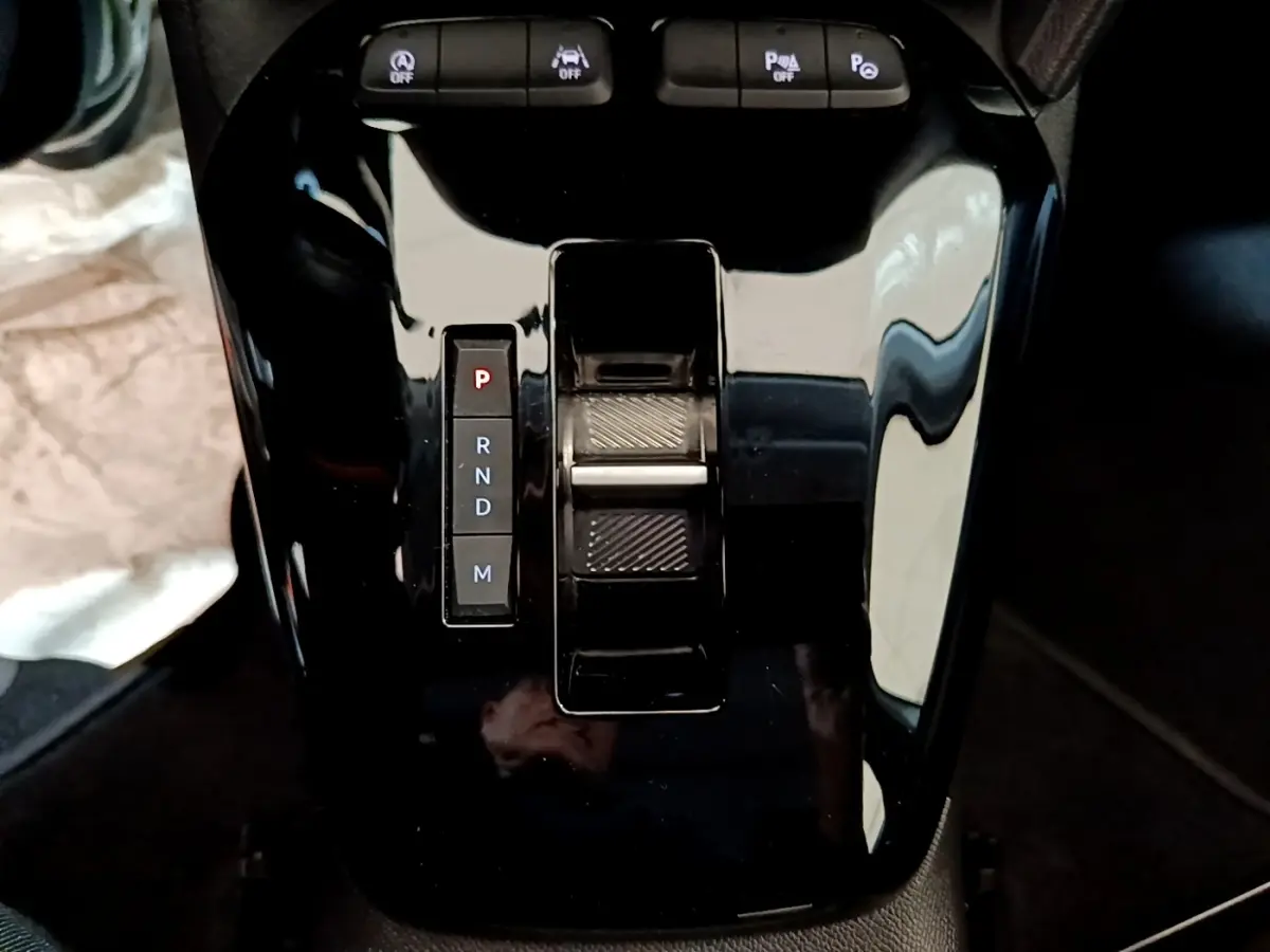 Gros plan sur la console centrale noire brillante de l’Opel Corsa 1.2 Turbo, avec sélecteur de boîte automatique et boutons de contrôle.
