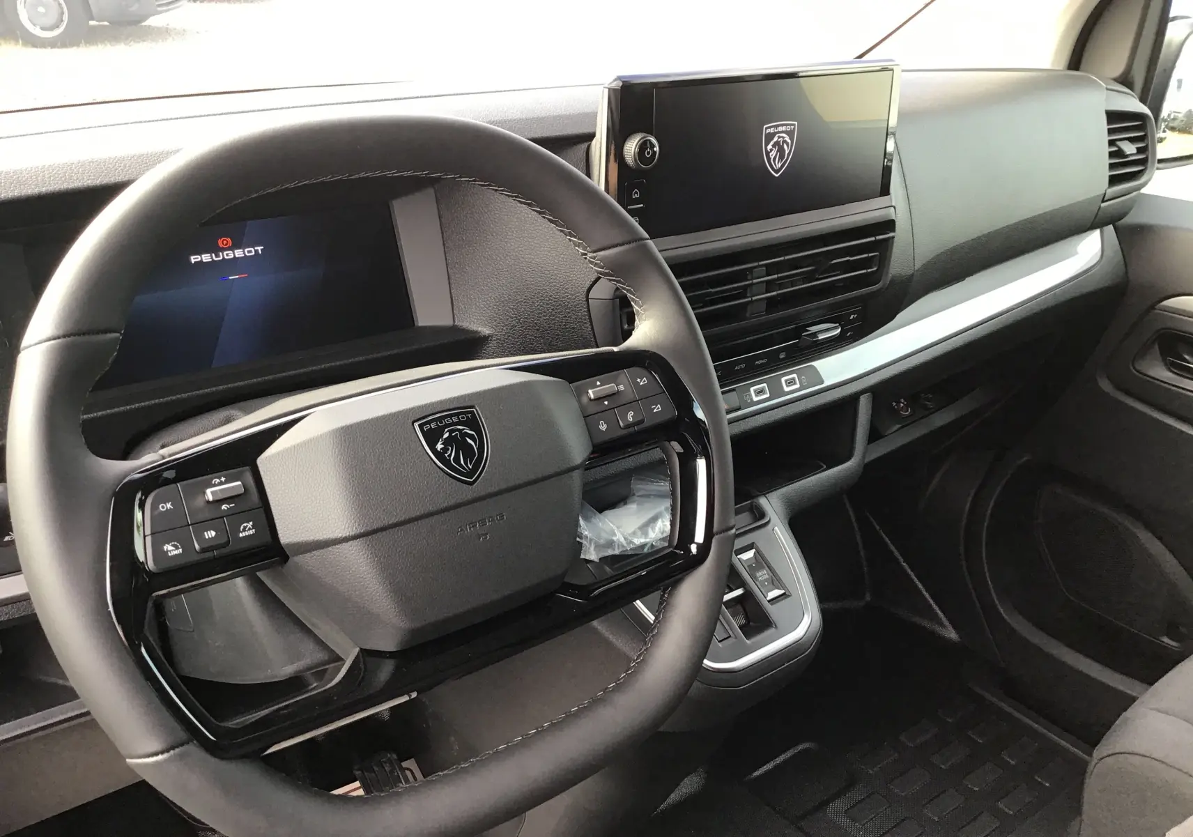 Vue intérieure du poste de conduite du Peugeot Expert Cabine Approfondie noir, avec volant compact et écran tactile central.