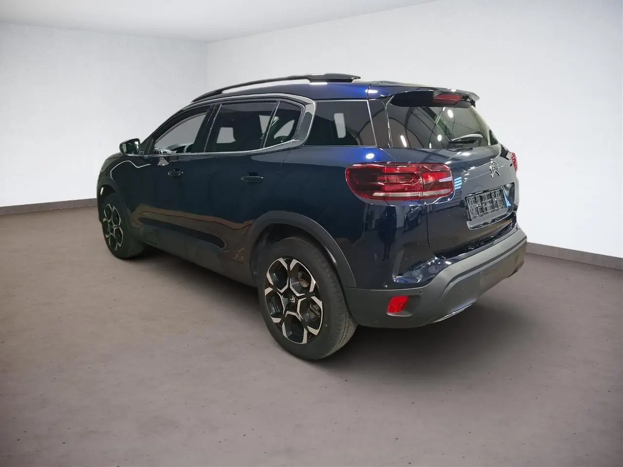 Vue 3/4 arrière droit du Citroën C5 Aircross Bleu Eclipse avec jantes alliage et barres de toit noires.