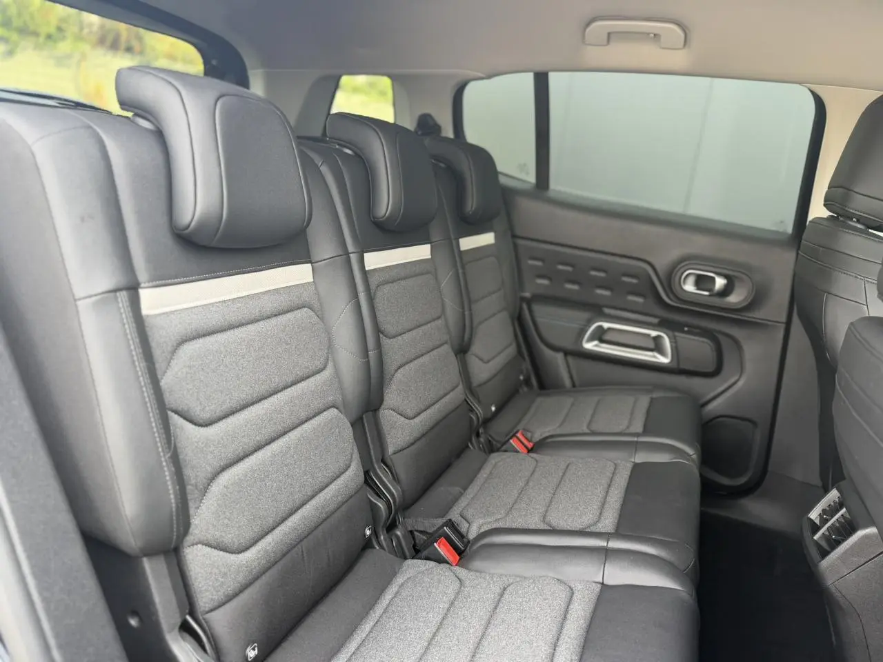 Vue latérale droite des trois sièges arrière indépendants gris et noirs du Citroën C5 Aircross 2025, avec appuis-tête et ceintures visibles.